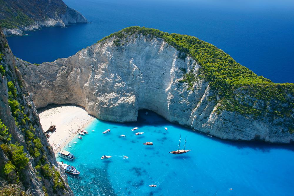 secret cove in greece with small sailboats anchored