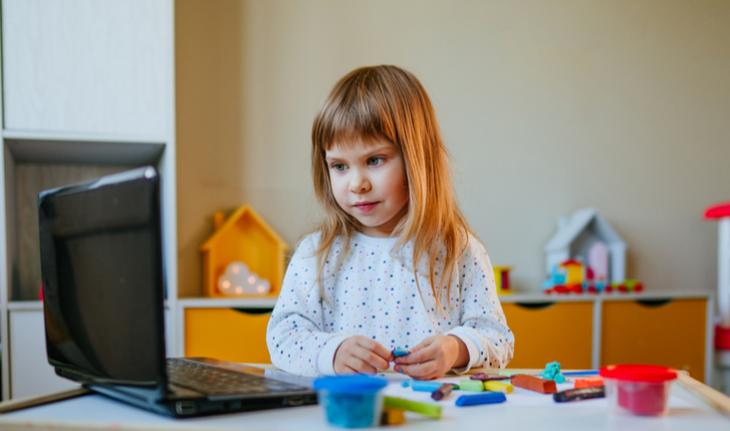 girl building blocks in front of laptop